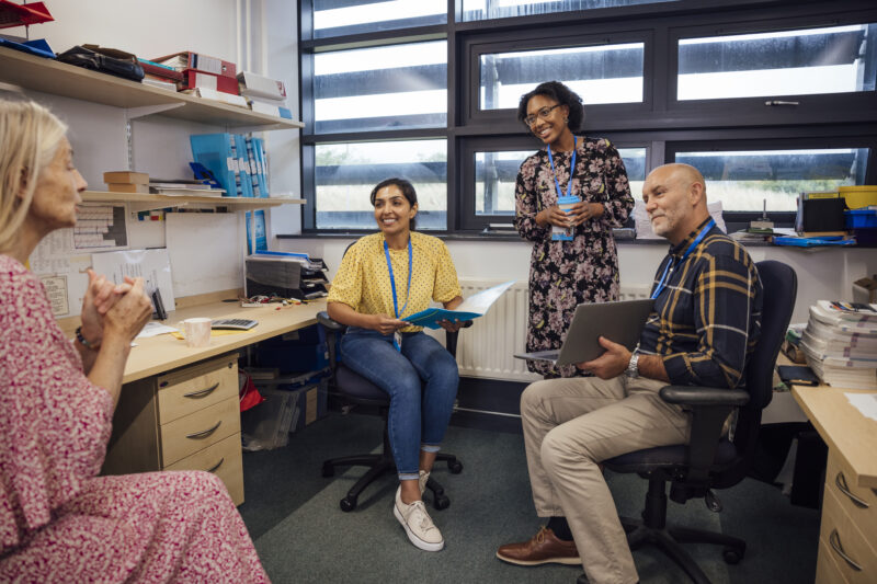 A shot of a small group of teachers discussing work in a meeting