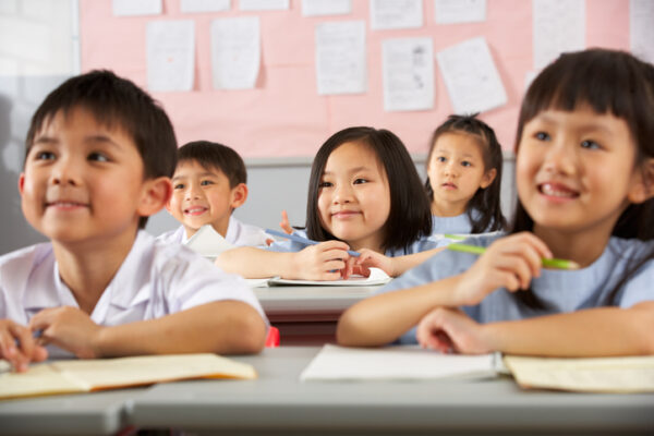 Group Of Students Working At Desks In Chinese School Classroom