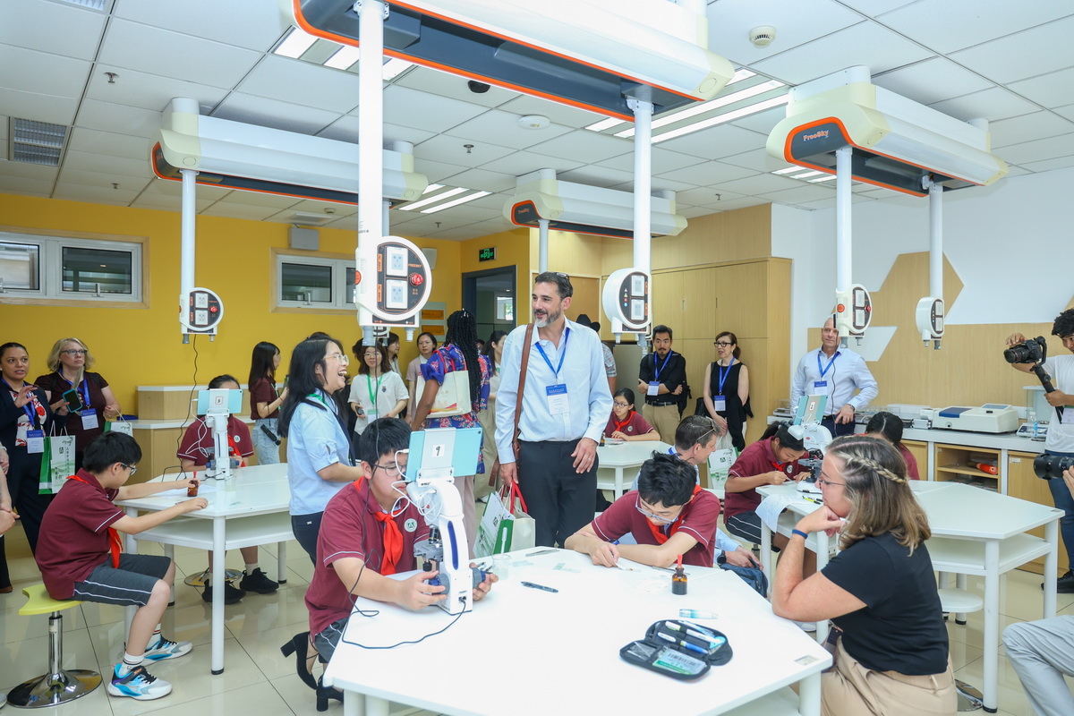 Visitors at a secondary school in Shanghai, watch as students use microscopes in a high-tech classroom.